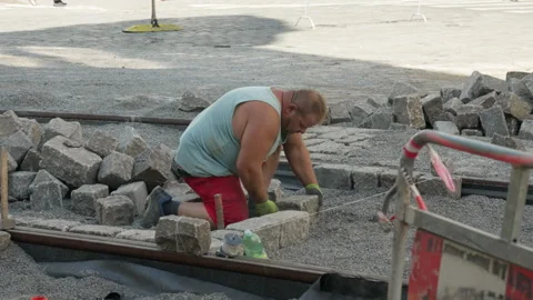 Construction Worker Kneels And Paves Granite Cobblestones On Prague Street 動画素材 342279797
