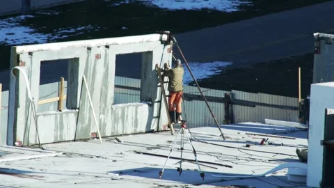 Construction worker on ladder adjusting precast concrete wall panel with window Stock Footage 323913092