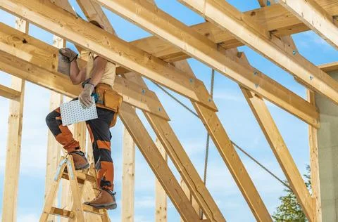 Construction Worker on Ladder Assembling Wooden Beams in Bright Daylight Du.. Stock Photos