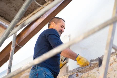 Construction worker on a ladder fixing a wall Foto stock