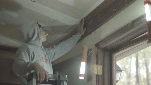 Construction worker on ladder looks at wall Stock Footage 144293788