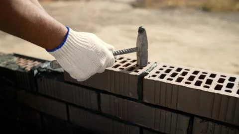 Construction worker laying bricks and building a wall with hammer and mortar Stock Photos