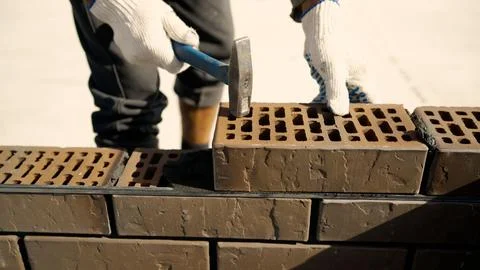 Construction worker laying bricks with hammer and cement Stock Photos