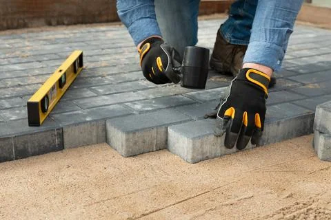 Construction worker laying cement pavement on a walkway with gloves and rub.. Stock Photos