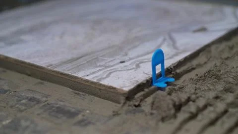 Construction worker laying ceramic tile using tile leveling system. Stock Photos