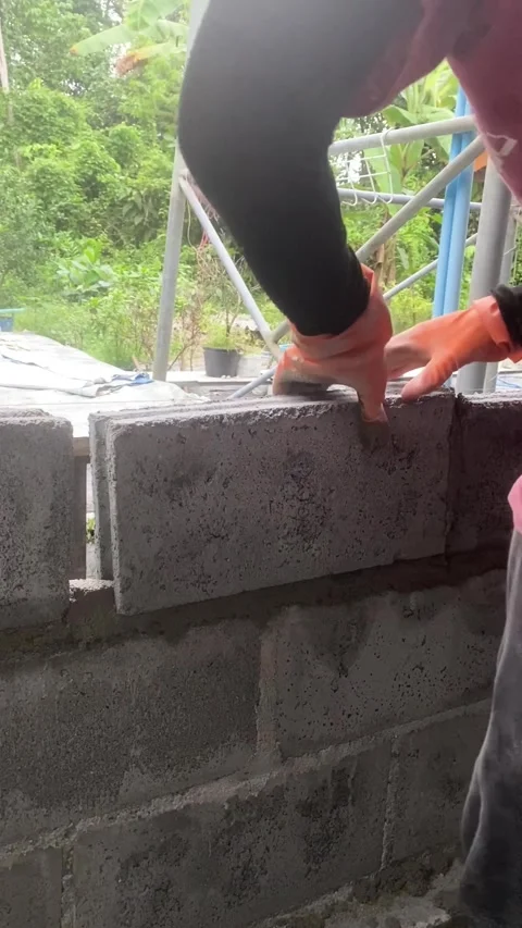 Construction worker laying concrete blocks with cement mortar at building site. Video stock 332565883