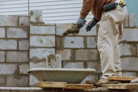 Construction worker laying of concrete blocks bricklaying new house wall Stock Photos