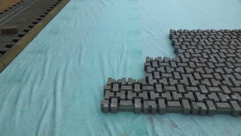 Construction worker laying interlocking paving concrete onto sheet nonwoven b Vídeo Stock 99605069
