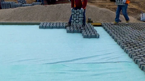 Construction worker laying interlocking paving concrete onto sheet nonwoven b Stock-Footage 99605333