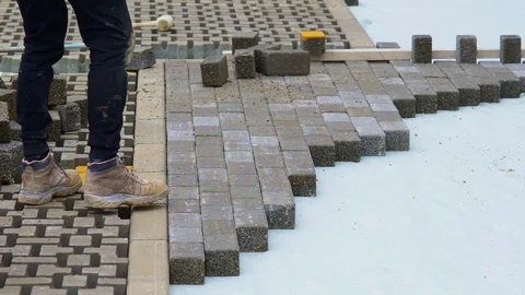 Construction worker laying interlocking paving concrete onto sheet nonwoven b Stock-Footage 105878809