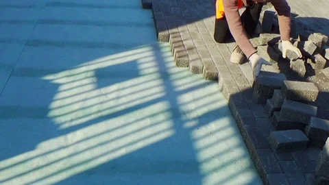 Construction worker laying interlocking paving concrete onto sheet nonwoven b Stock-Footage 107188479
