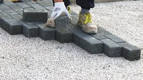 Construction worker laying interlocking paving concrete onto sheet nonwoven b Vídeo Stock 123535975