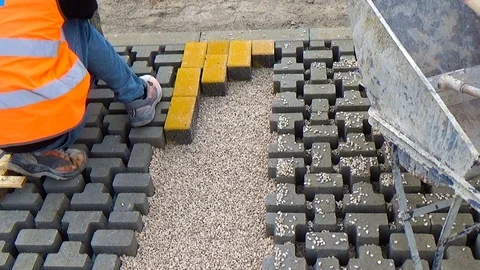 Construction worker laying interlocking paving concrete onto sheet nonwoven b Vídeo Stock 123536112
