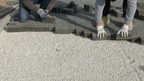 Construction worker laying interlocking paving concrete onto sheet nonwoven b Vídeo Stock 124011049