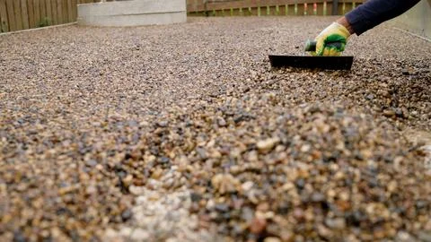 Construction worker laying a resin bound gravel patio floor with a trowel, .. Stock-Fotos