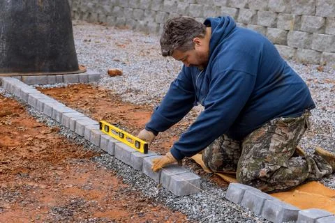 A construction worker laying stone concrete pavers as part of a sidewalk Stock Photos