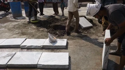 Construction worker lays stone slab on pavement Stock Footage 83635375