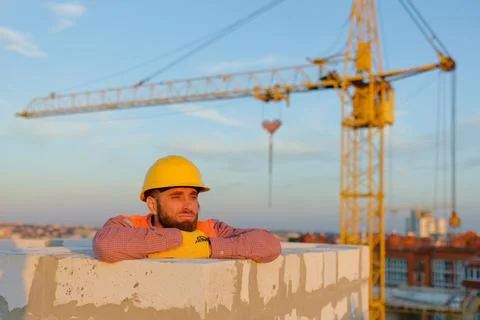 Construction worker leaning on wall with crane in background Stock Photos