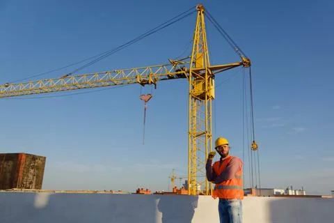 Construction worker leaning on wall with crane in background Stock Photos