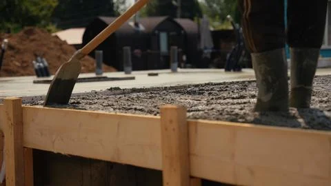 Construction worker leveling concrete foundation at building site Stock Photos