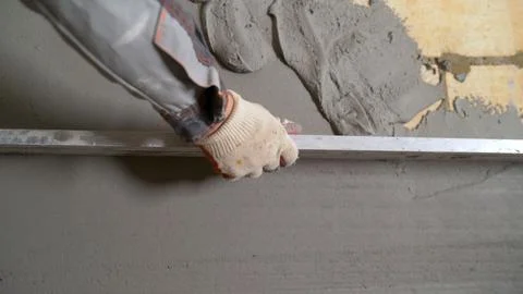 Construction worker leveling concrete mortar using aluminum straight edge Stock Photos