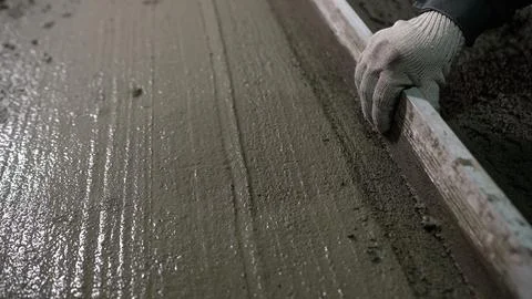Construction worker leveling concrete surface with a screed tool Stock Photos