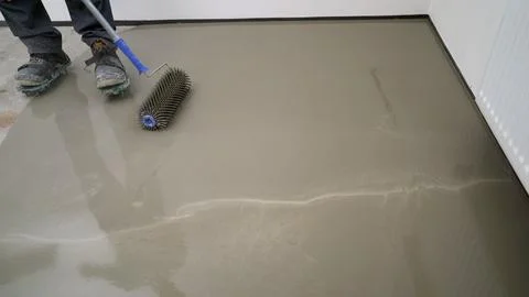 Construction worker leveling concrete surface with spiked roller Stock Photos