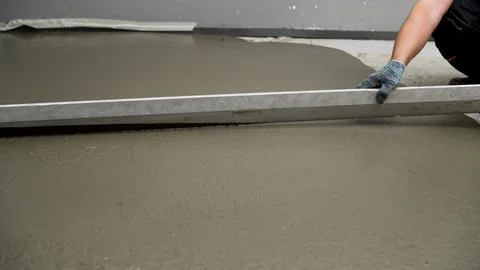 Construction worker leveling concrete surface with a screed Stock Photos