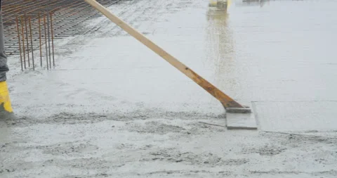 Construction Worker Leveling Fresh Concrete with a Rake on a Building Site Stock Footage 315431633