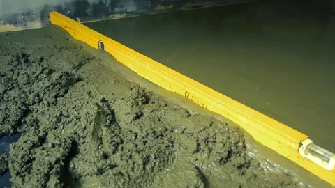 Construction worker leveling freshly poured concrete floor with a level tool Stock Footage 346492334