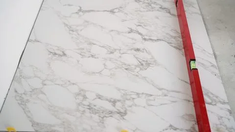 Construction worker leveling marble tile during floor installation Stock Photos