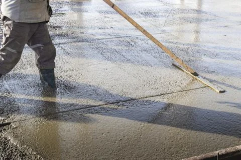 Construction worker leveling a poured concrete floor Stock Photos