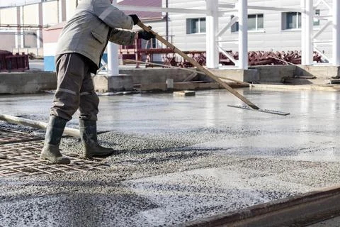 Construction worker leveling a poured concrete floor Stock Photos