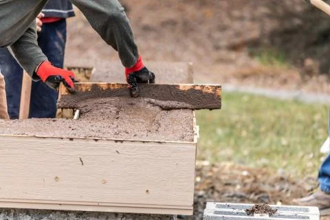 Construction Worker Leveling Wet Cement Into Wood Framing. Stock Photos