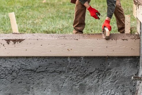 Construction Worker Leveling Wet Cement Into Wood Framing. Stock Photos