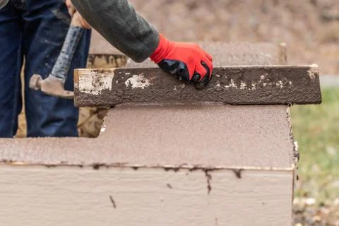Construction Worker Leveling Wet Cement Into Wood Framing. Stock Photos