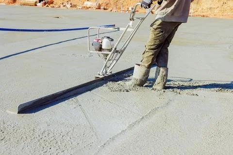Construction worker leveling wet concrete on building site during works day Stock Photos