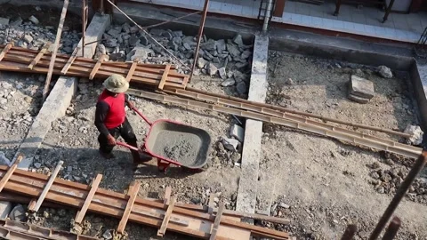 A construction worker lifts cement mortar with a wheelbarrow Stock Footage 160481197