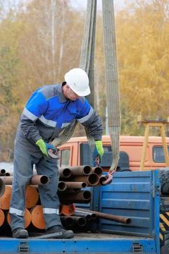 Construction Worker Loading Pipes onto Truck Stock Photos