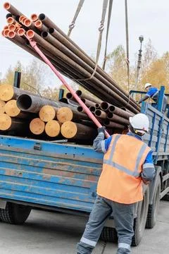 Construction Worker Loading Pipes onto Truck at Job Site Stock Photos