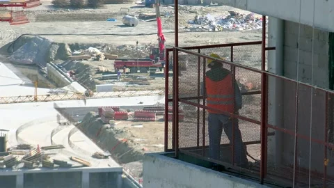 Construction worker looks down from balcony with safety helmet - High Landscape Stock Footage 339793385