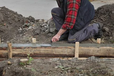 Construction worker making concrete foundation in formwork Stock Photos