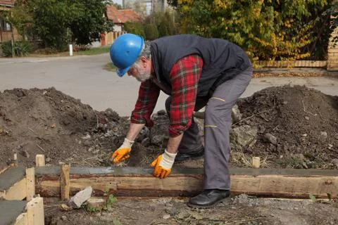 Construction worker making concrete foundation in formwork Stock Photos