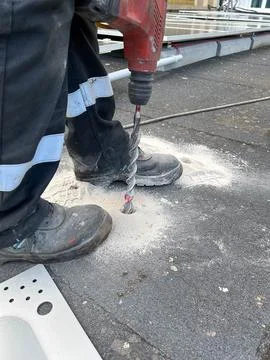 Construction worker making a hole in the concrete floor with a drill Stock Photos