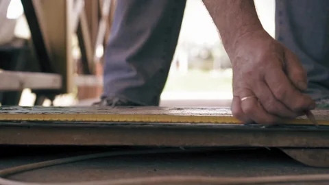 Construction worker is making marks on a wooden plank with pencil. Slow motion. Stock Footage 90135927