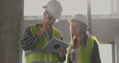 Construction worker man and architect woman in a helmet, discuss the plan of Video stock 112335006