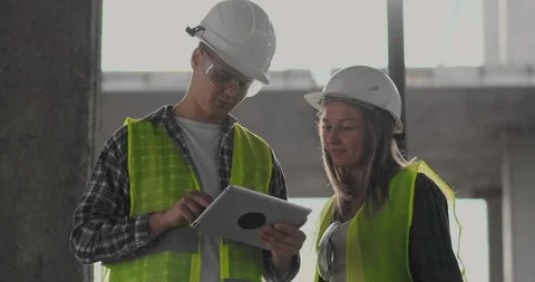 Construction worker man and architect woman in a helmet, discuss the plan of Video stock 112335139