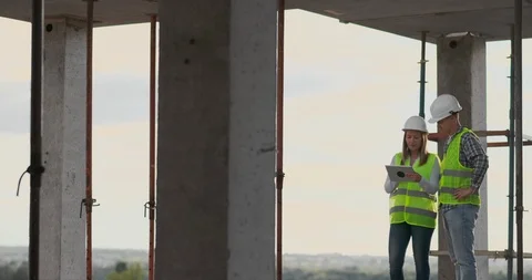 Construction worker man and architect woman in a helmet, discuss the plan of Video stock 112335296