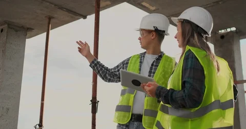 Construction worker man and architect woman in a helmet, discuss the plan of Video stock 112335417