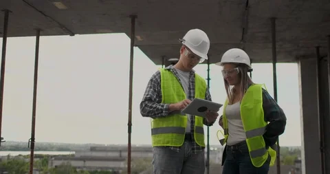 Construction worker man and architect woman in a helmet, discuss the plan of Stock Footage 112335606